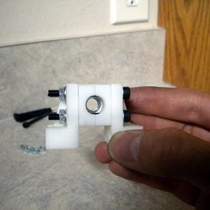 This is a nut trap and it is how the rotational motion of the threaded rod is transferred into linear motion along the Z-axis